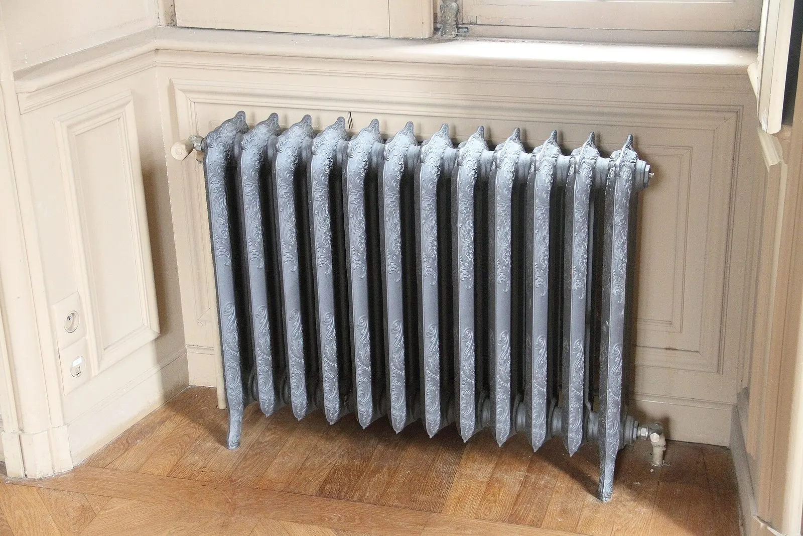 Radiateur en fonte ancien sous une fenêtre à boiseries